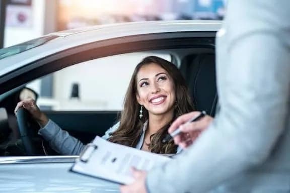 A smiling driver receiving the keys to her newly insured car